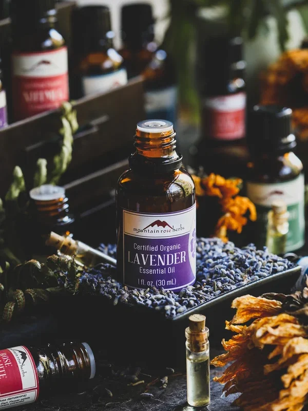 An amber glass bottle of lavender essential oil, surrounded by other bottles of essential oils from Mountain Rose Herbs.