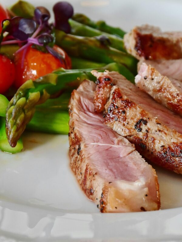 Close-up of grilled steak slices with asparagus and cherry tomatoes, perfect for a healthy meal. whole food deep nutrition