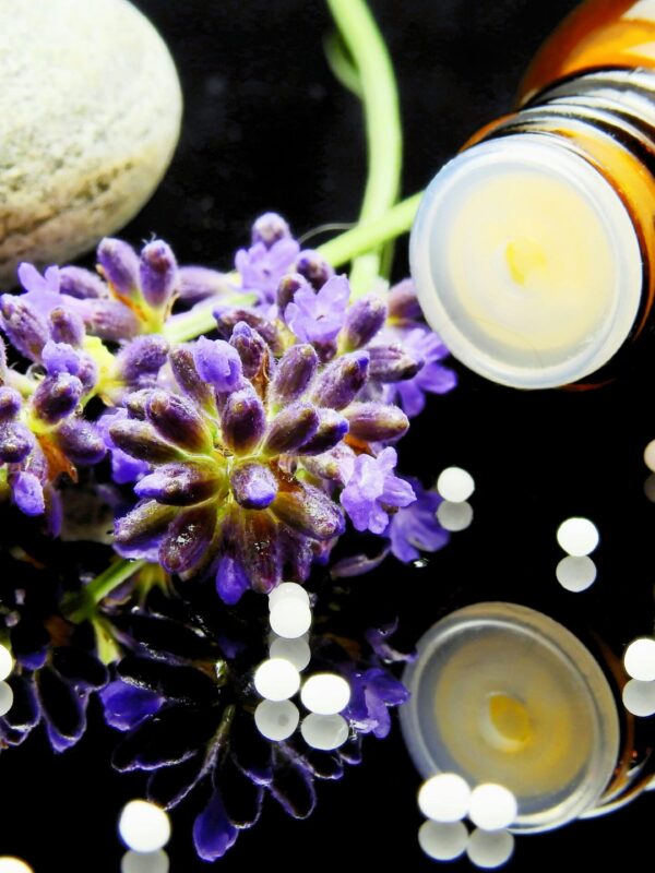 Lavender flowers with herbal homeopathy at home on a reflective surface, ideal for natural therapy themes.