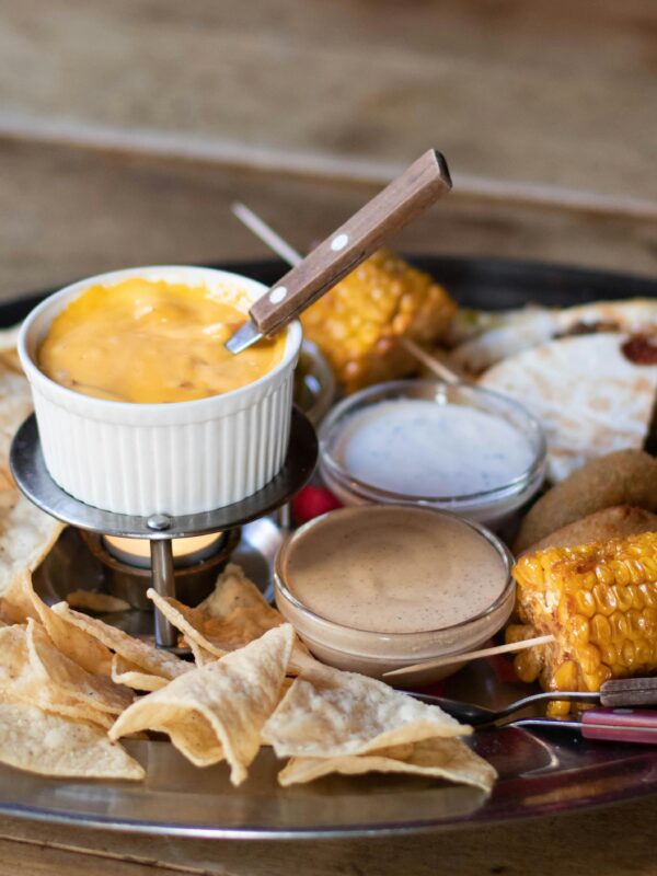 Mexican platter featuring cheese dip, corn, quesadillas, and chips.