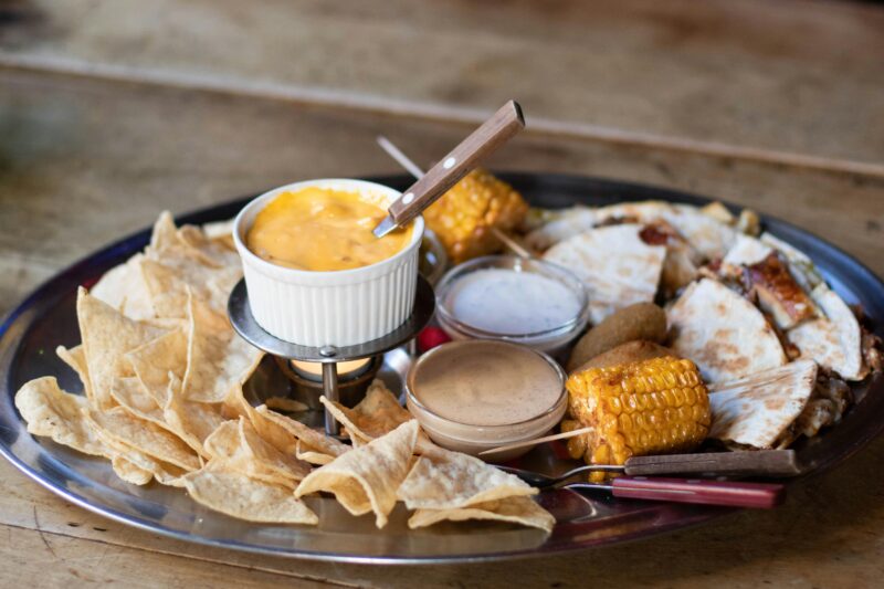 Mexican platter featuring cheese dip, corn, quesadillas, and chips.