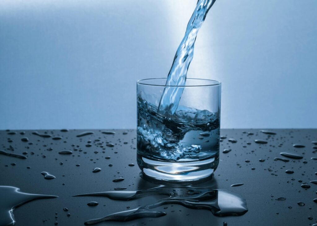 High-quality image of water being poured into a glass, illustrating hydration purity. and proone water filter