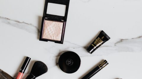 Top view of makeup essentials arranged on a marble surface, highlighting beauty products, tools, and attitude oceanly blush stick.