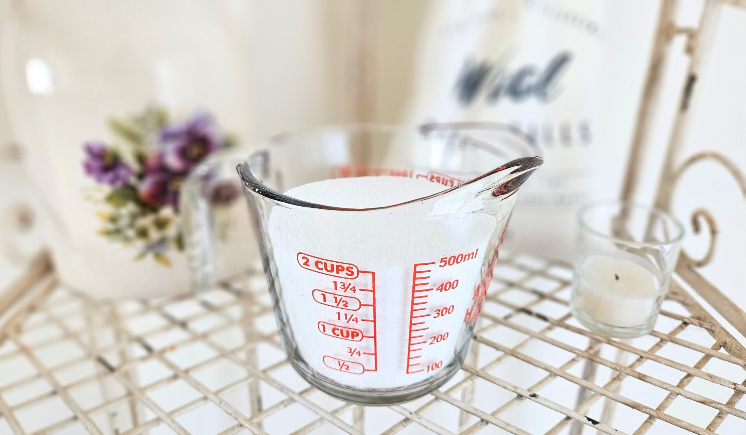 A glass measuring cup filled with two cups of washing soda. Washing soda is a white powdery mixture.
