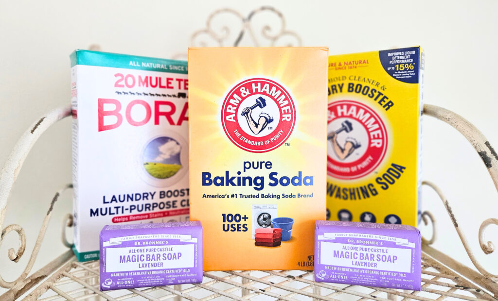 One box of borax. One box of baking soda. One box of washing soda. Two bars of Dr. Bronner's lavender castile soap. All sitting on a metal wire rack.