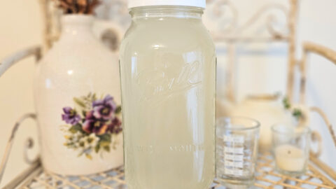 Half gallon mason jar filled with light yellow homemade liquid laundry detergent.