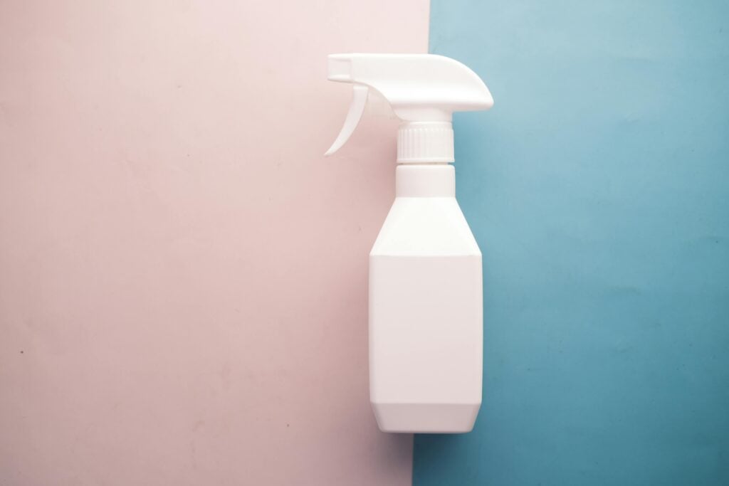 White spray bottle of Better Than Clean on pink and blue background with copy space, perfect for product mockups.