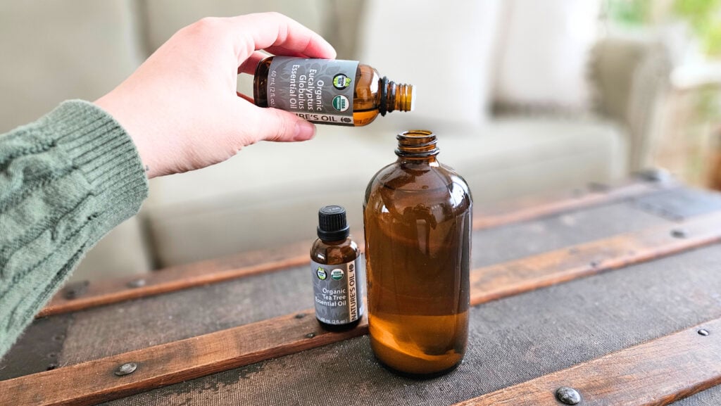 Adding eucalyptus essential oil to an amber glass spray bottle.