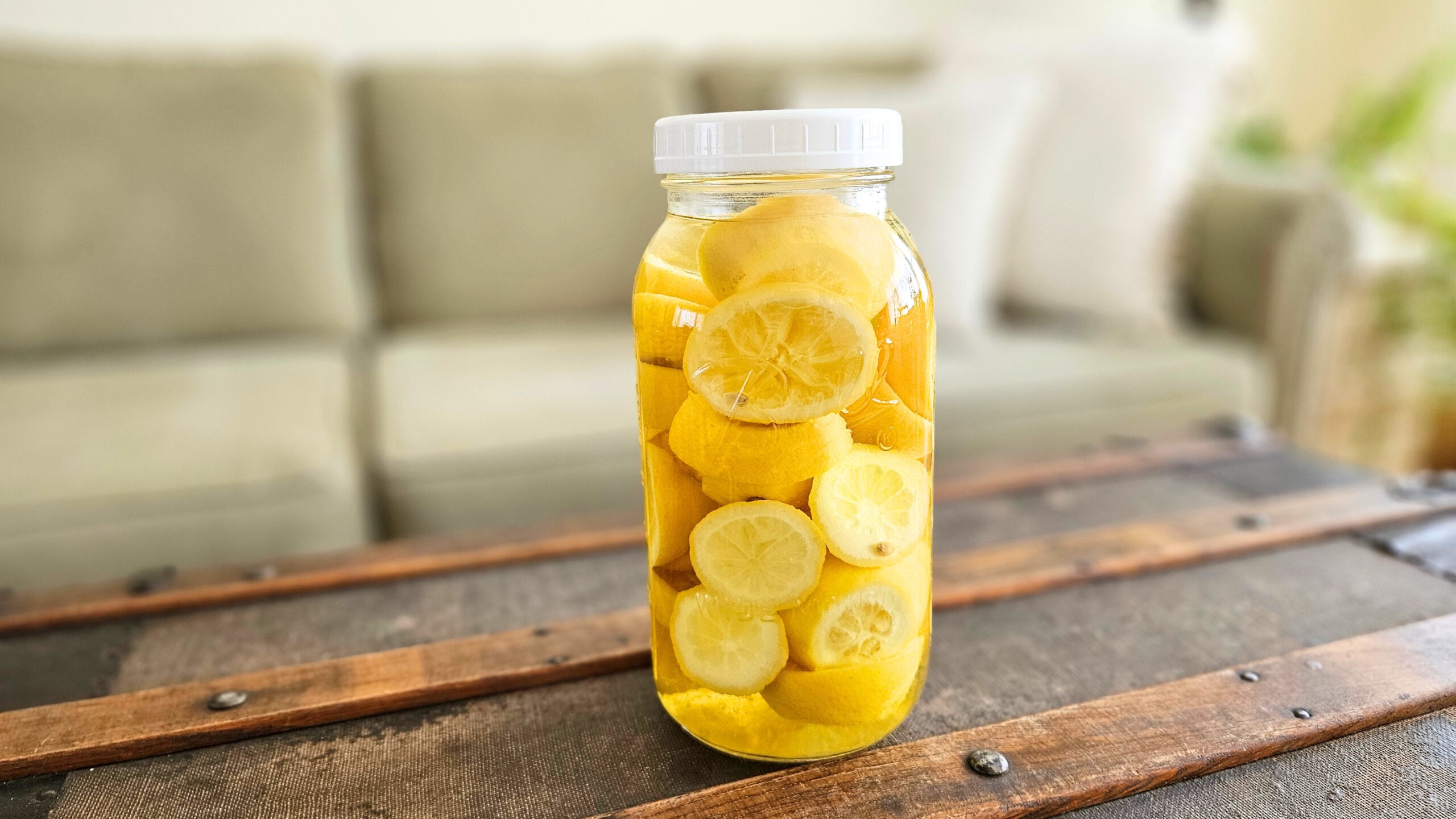 A half gallon mason jar of lemons and distilled white vinegar.