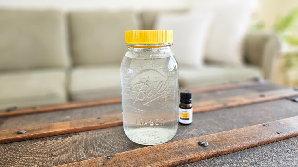 Jar of liquid fabric softener and a bottle of lemon essential oil.