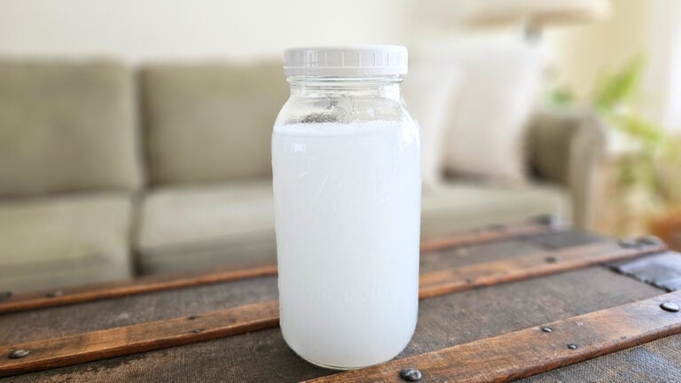 Half gallon mason jar of homemade liquid fabric softener sitting on top of a trunk.