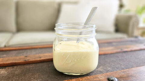 Homemade mayo in a glass jar with a spoon.