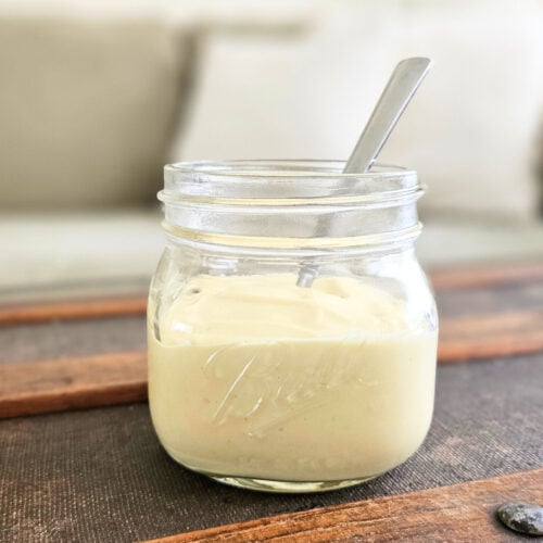 Homemade mayo in a glass jar with a spoon.