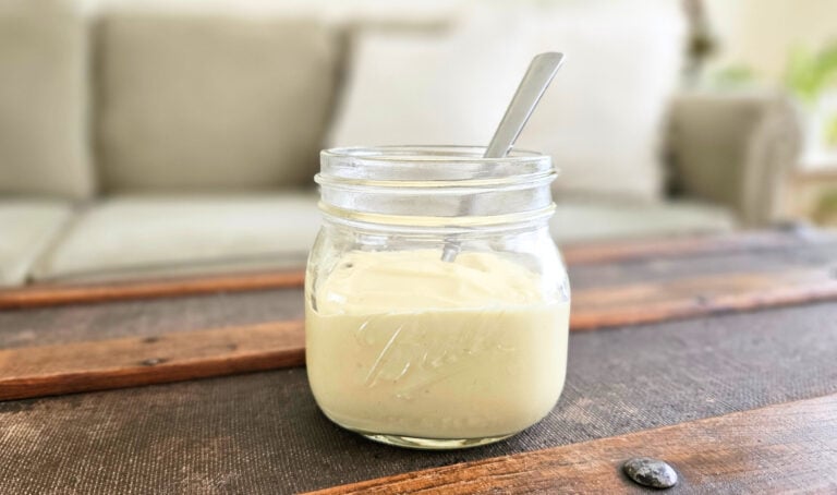 Homemade mayo in a glass jar with a spoon.