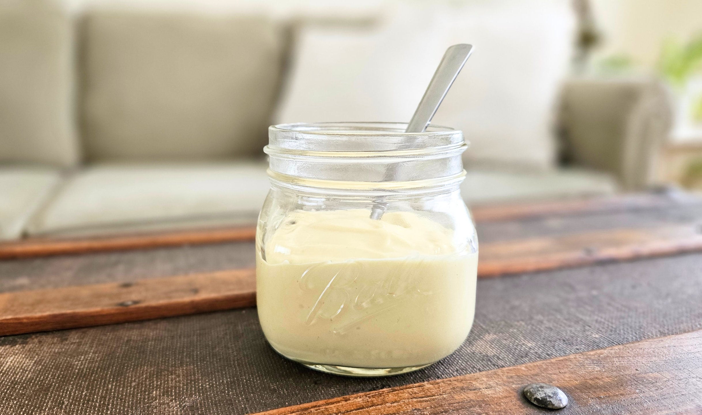 Homemade mayo in a glass jar with a spoon.