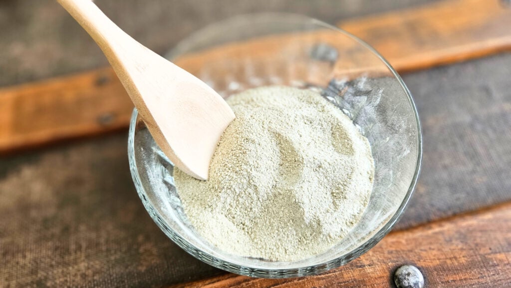 Thoroughly mixed tooth brushing powder in a glass bowl with a wooden spoon.