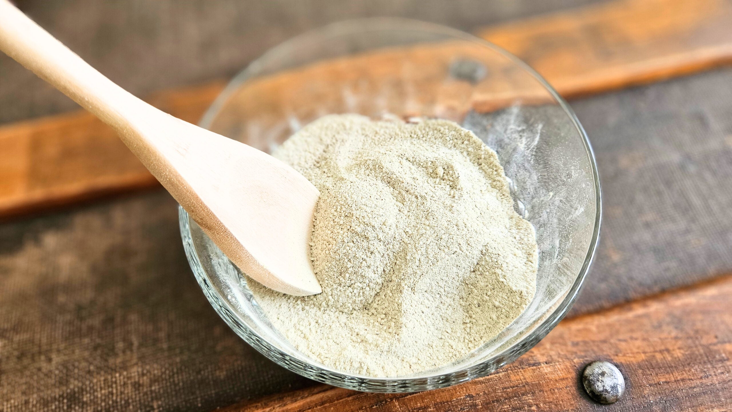 Wooden spoon mixing together tooth brushing powder ingredients.