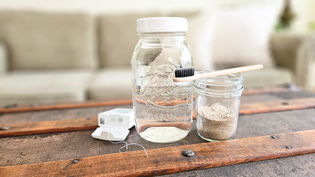 Quart jar with homemade mouthwash, tooth brushing powder, bamboo toothbrush, and floss.